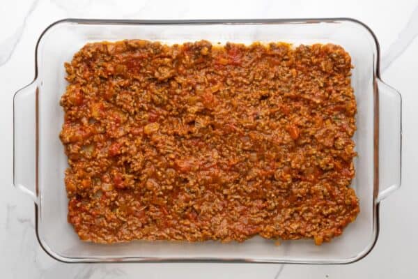 a layer of meat sauce in a clear glass 9x13-inch baking dish.