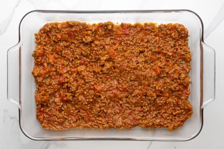 a layer of meat sauce in a clear glass 9x13-inch baking dish.