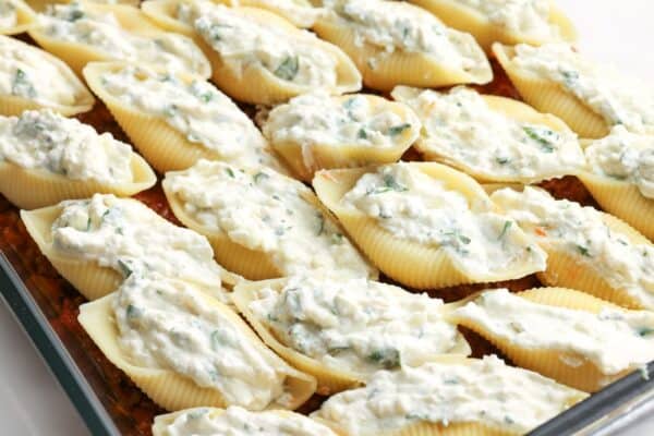 cheese stuffed shells arranged neatly over meaty tomato sauce in a casserole dish.