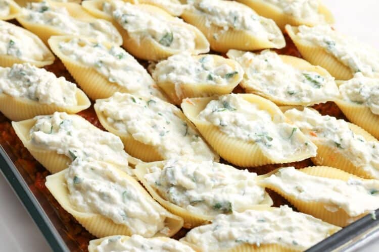 cheese stuffed shells arranged neatly over meaty tomato sauce in a casserole dish.