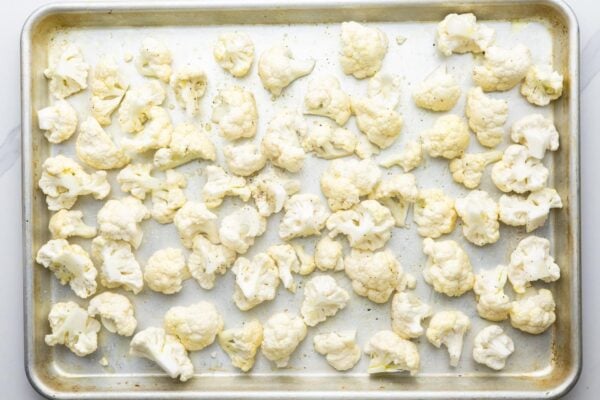 cauliflower florets on a sheet pan, coated in oil and seasonings.