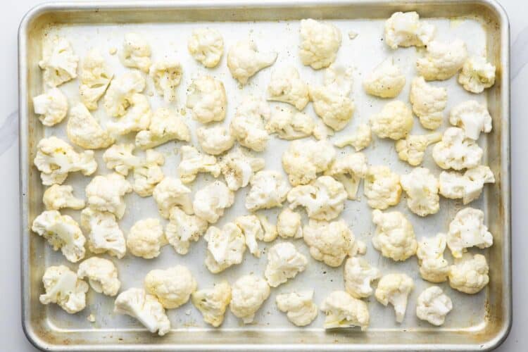 cauliflower florets on a sheet pan, coated in oil and seasonings.