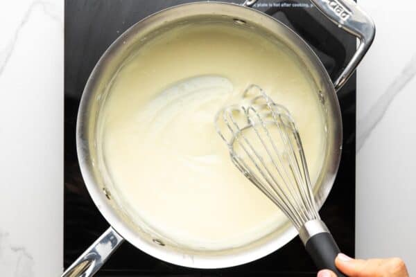 Thickened cream sauce whisked in a saucepan.