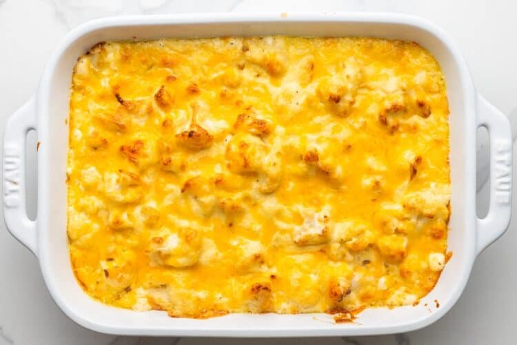 baked cauliflower cheese in a white ceramic baking dish.