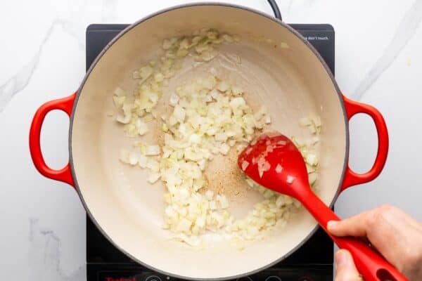 diced onions sauteing in a dutch oven, stirred with a spoon.