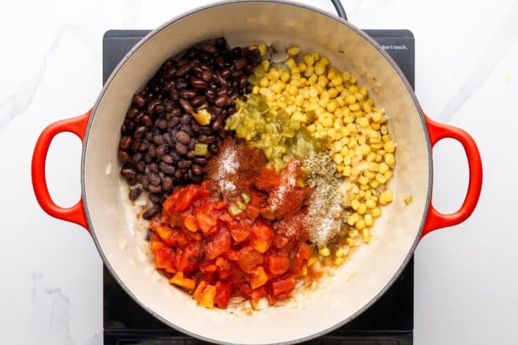 canned tomatoes, corn, green chilies, and black beans added to a dutch oven for chicken tortilla soup.