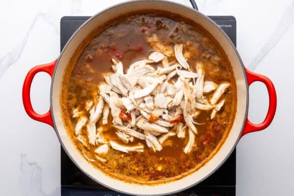 shredded white meat chicken added to a pot of tortilla soup.