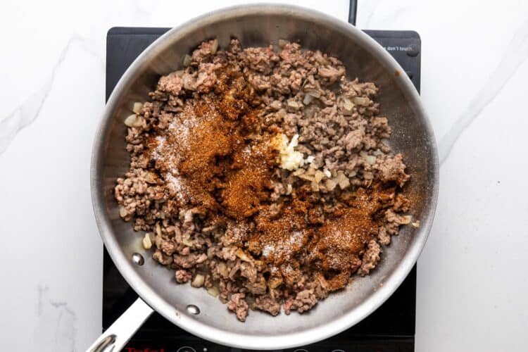 cooked ground beef in a skillet, with taco seasonings added