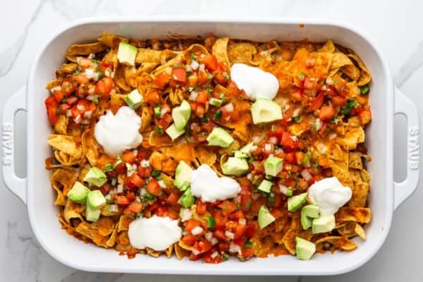 baked frito pie, topped with dollops of sour cream, diced avocado, and pico de gallo.