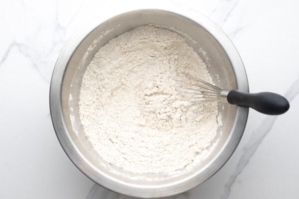 dry ingredients for gingerbread men cookies whisked in a metal mixing bowl.
