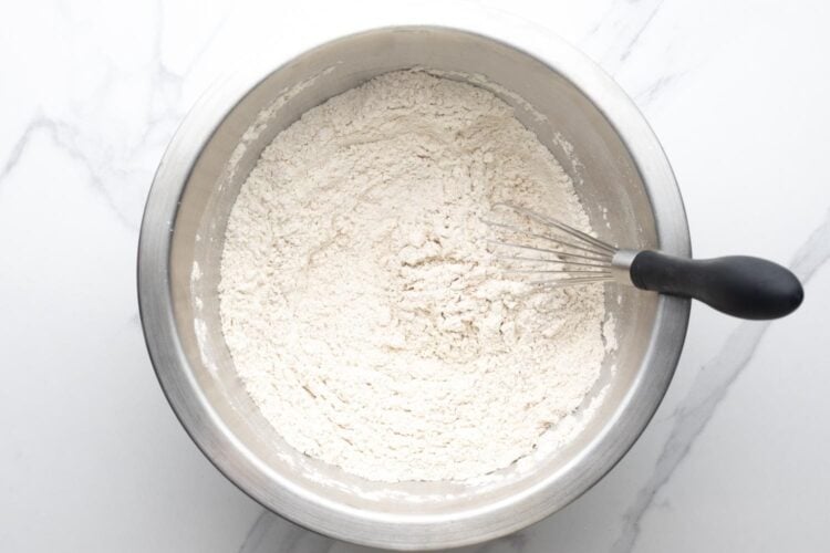 dry ingredients for gingerbread men cookies whisked in a metal mixing bowl.
