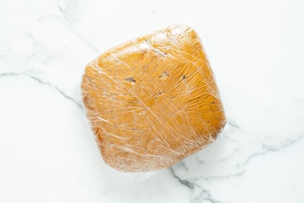 gingerbread cookie dough pressed into a square shape and wrapped with plastic wrap.