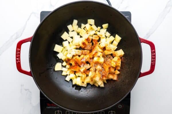 seasoned diced potatoes cooking in a two handled skillet.