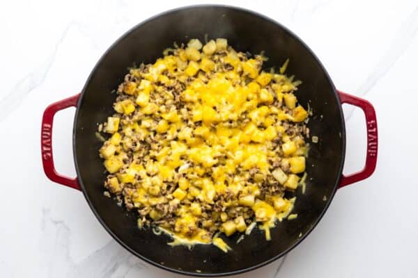 ground beef and potatoes in a skillet, topped with melted cheese.