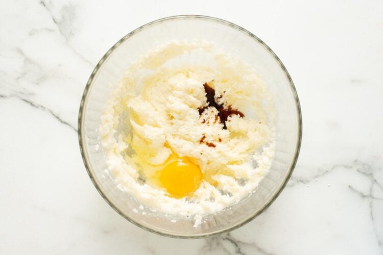vanilla and an egg added to creamed butter and sugar in a large glass mixing bowl.