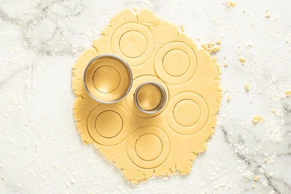 sugar cookie dough rolled out on a lightly floured counter, cut into circles with cookie cutters for stained glass cookies.