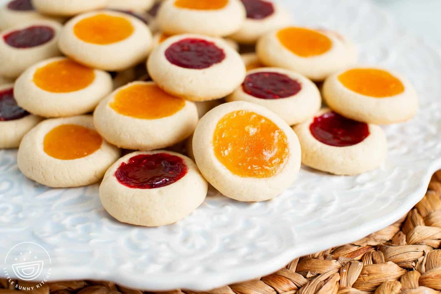 a plate of apricot and raspberry thumbprint cookies filled with jam.