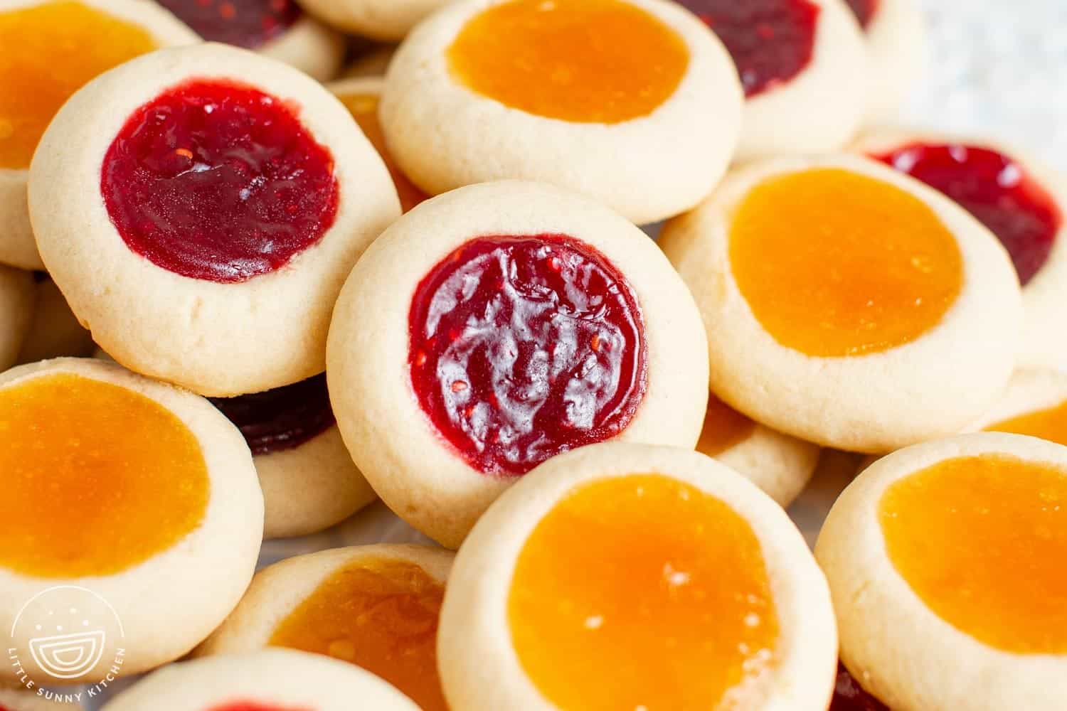 closeup of raspberry and apricot thumbprint cookies.