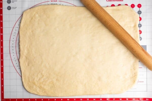 cinnamon roll dough rolled out into a rectangle that is about 20 inches long by 14 inch tall.