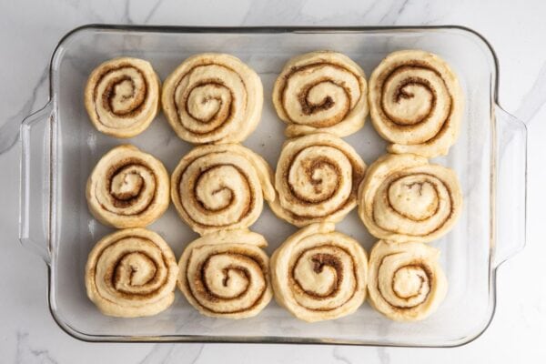 unbaked cinnamon rolls in a glass 9x13-inch baking dish.