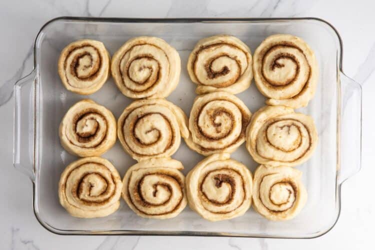 unbaked cinnamon rolls in a glass 9x13-inch baking dish.