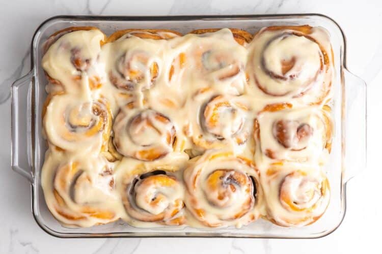overhead view of a pan of twelve bread machine cinnamon rolls set on a marble counter.