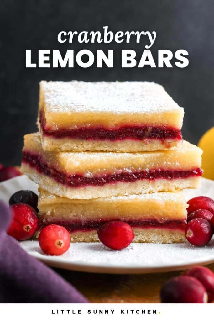 Three layered cranberry lemon bars on a small white plate, garnished with fresh cranberries. The text overlay at the top of the photo says "cranberry lemon bars"