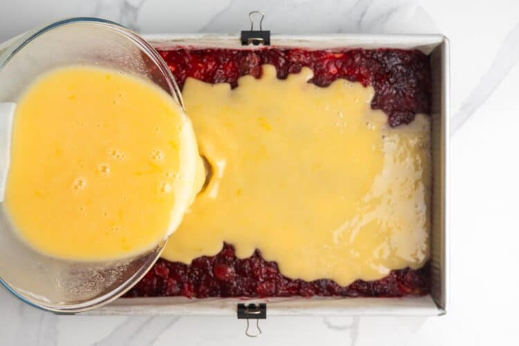 lemon mixture poured over a layer of cranberries for lemon cranberry bars.