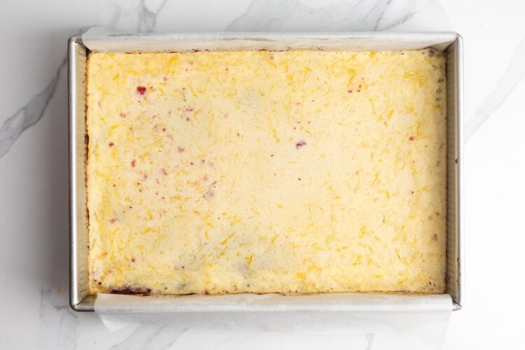 baked lemon cranberry bars, viewed from overhead in a metal pan. The top layer is barely set.