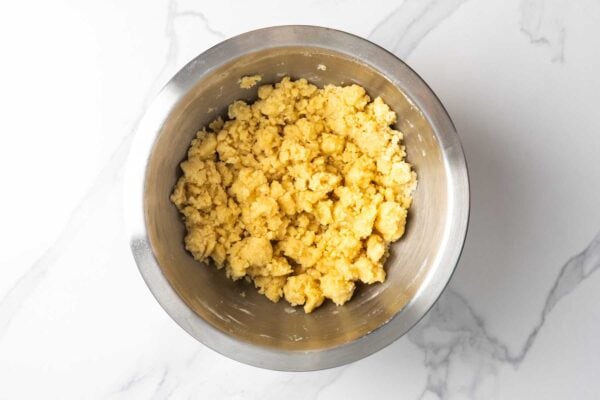 crumbly dough mixture for the bottom layer of lemon bars in a metal mixing bowl.