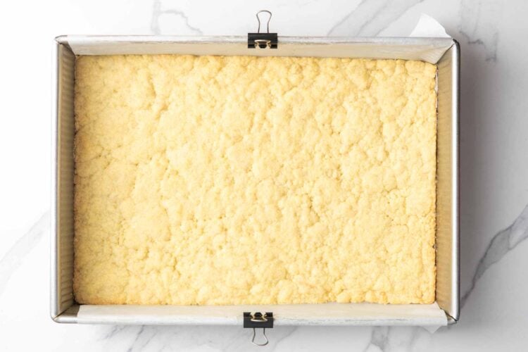 baked crust for lemon bars in a metal baking pan. The edges are lightly browned.