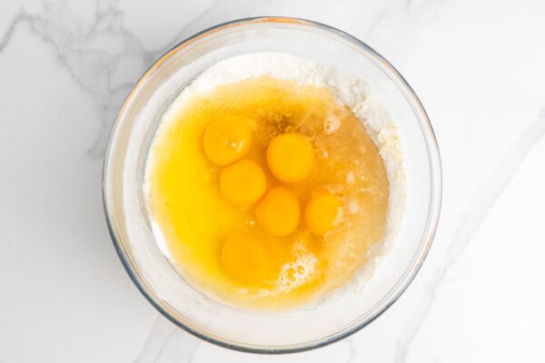 six eggs added to a bowl of lemon zest, flour, and sugar to make lemon mixture for lemon bars.