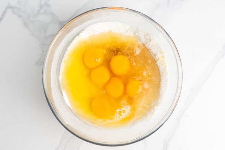 six eggs added to a bowl of lemon zest, flour, and sugar to make lemon mixture for lemon bars.