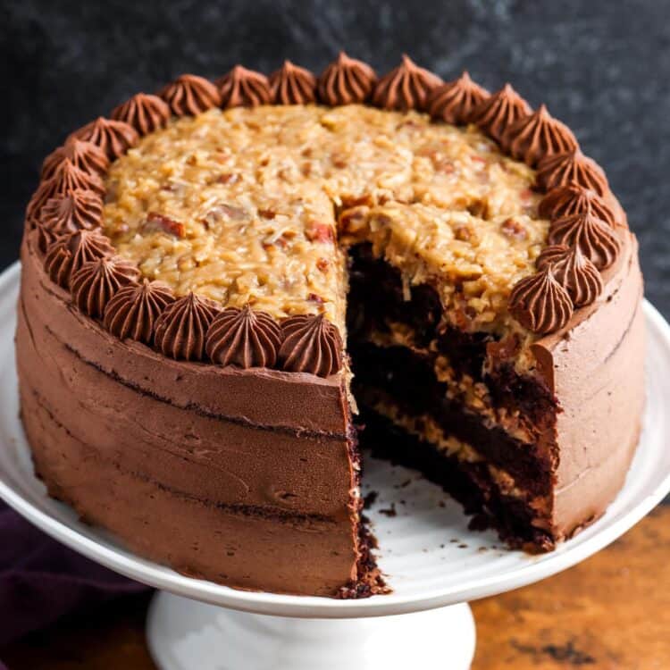 A german chocolate cake with three layers. One slice has been removed to show the pecan coconut filling.