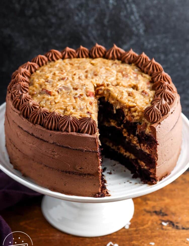 A german chocolate cake with three layers. One slice has been removed to show the pecan coconut filling.