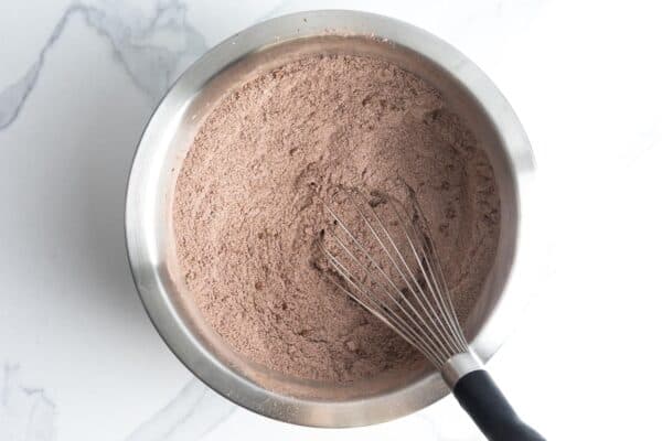 cocoa powder whisked with flour in a metal mixing bowl.