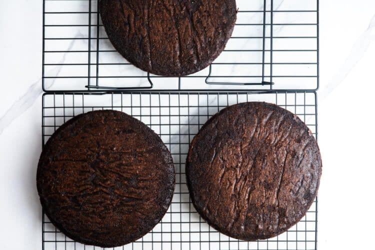 three round german chocolate cake layers, cooling on wire racks.