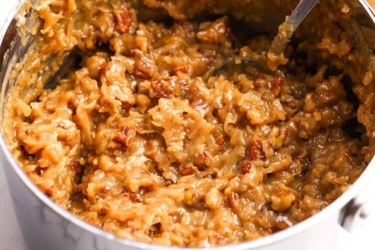 pecan coconut german chocolate cake filling in a saucepan, stirred with a spoon.