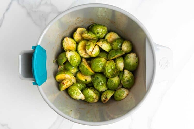 cleaned and halved brussels in a bowl with oil and seasonings.