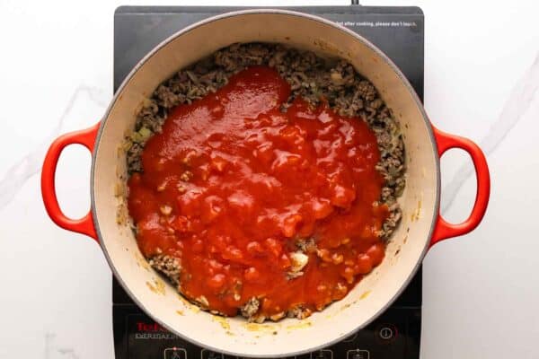 tomato sauce added to a pot of cooked ground beef.