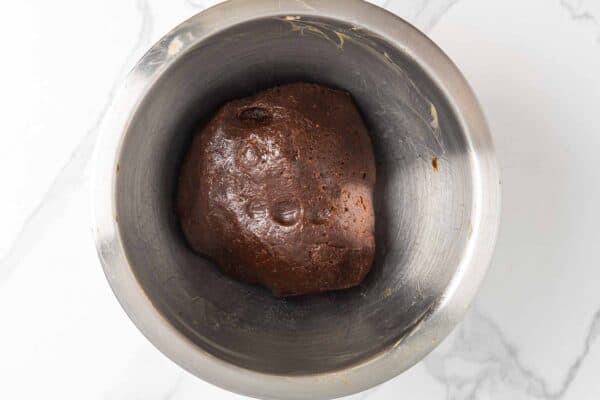 Date paste dough resting in a mixing bowl, formed into a smooth, dark ball.
