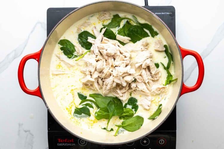 fresh baby spinach and shredded chicken added to a pot of creamy chicken soup.