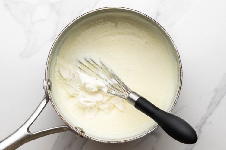 Mixing ricotta in the ashta in a saucepan
