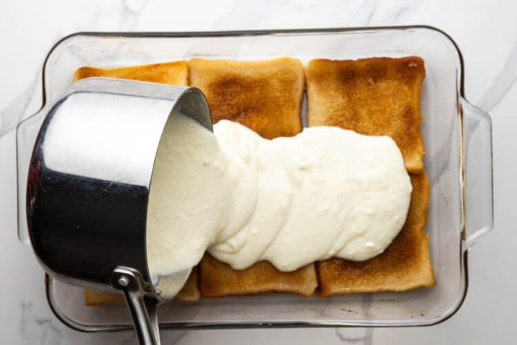 Pouring warm ashta on the syrup soaked toasted bread