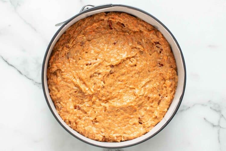 Carrot cake batter in a round springform pan.