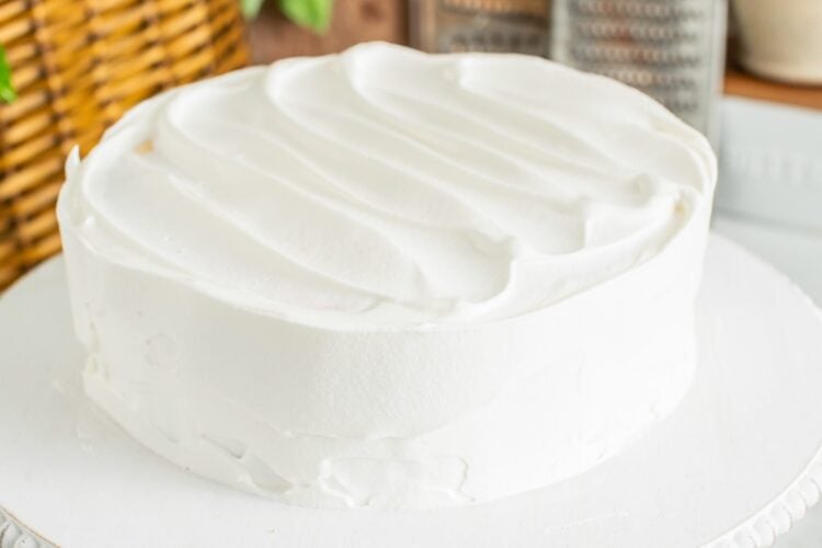 Carrot cake cheesecake on a platter, covered in whipped topping.