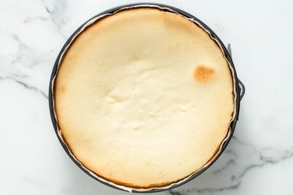 overhead view of a baked cheesecake in a springform pan with browned edges.