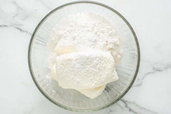 blocks of softened cream cheese in a mixing bowl with powdered sugar and cornstarch.