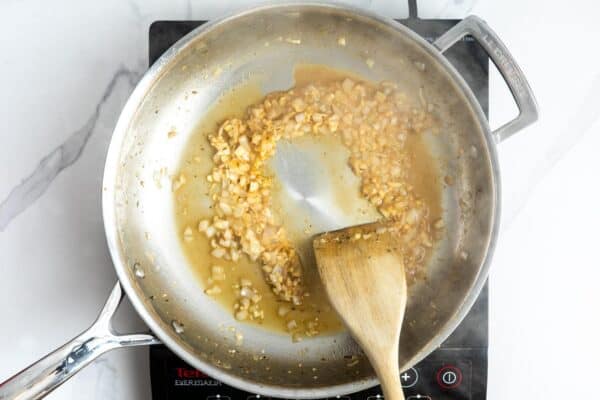 minced shallot and garlic cooking in a frying pan with oil.
