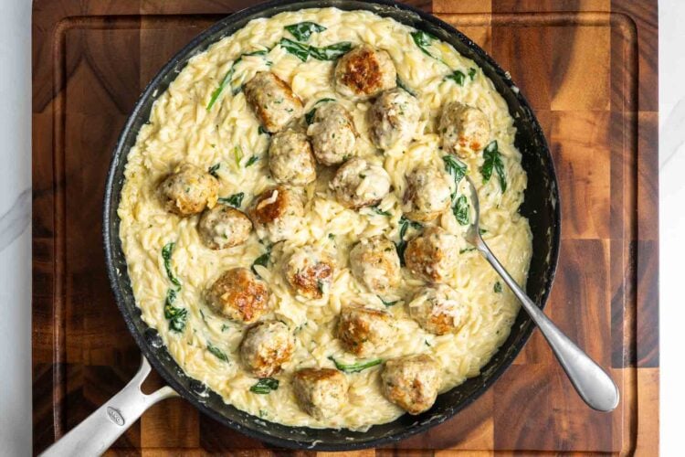 Finished skillet of browned chicken meatballs with lemon spinach orzo pasta.